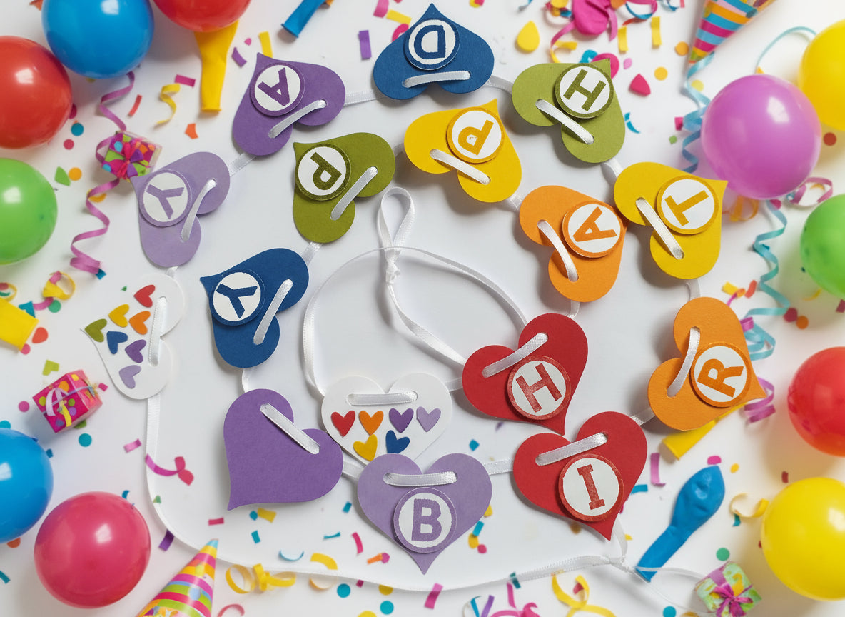 Colorful heart-shaped letter cookies on a white plate with balloons and streamers in the background.