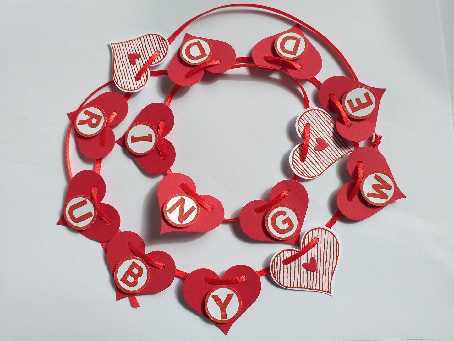 A handcrafted Ruby Wedding banner made of red satin ribbon with decorative red hearts and white text elements spelling 'RUBY WEDDING'.
