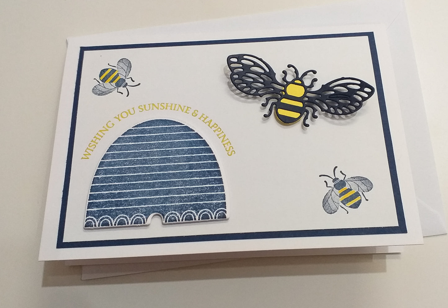 A hand-stamped and layered greeting card with a bee design and the words 'Wishing You Sunshine' on the front, accompanied by an envelope.