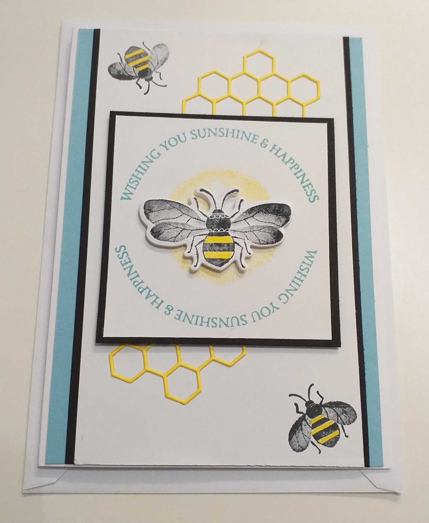 A colorful hand-crafted greeting card with a bee design and a message that reads 'Wishing You Sunshine & Happiness'. The card is blank inside and has a blue and yellow color scheme.