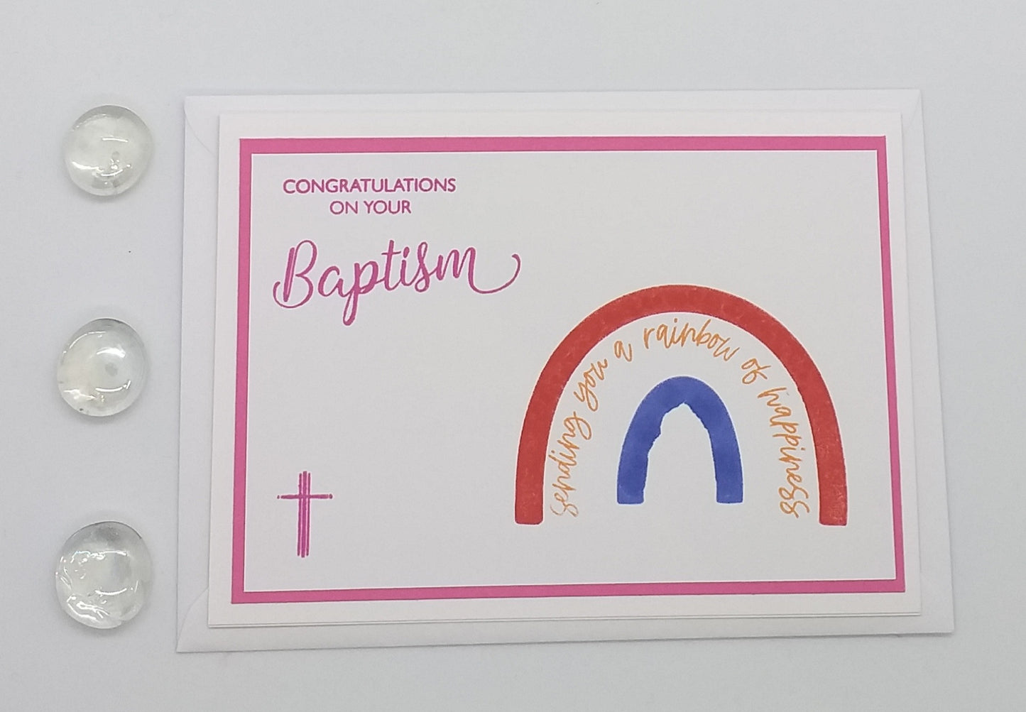 Greeting card with 'Congratulations on your Baptism' text and rainbow design in front of a stained glass window.
