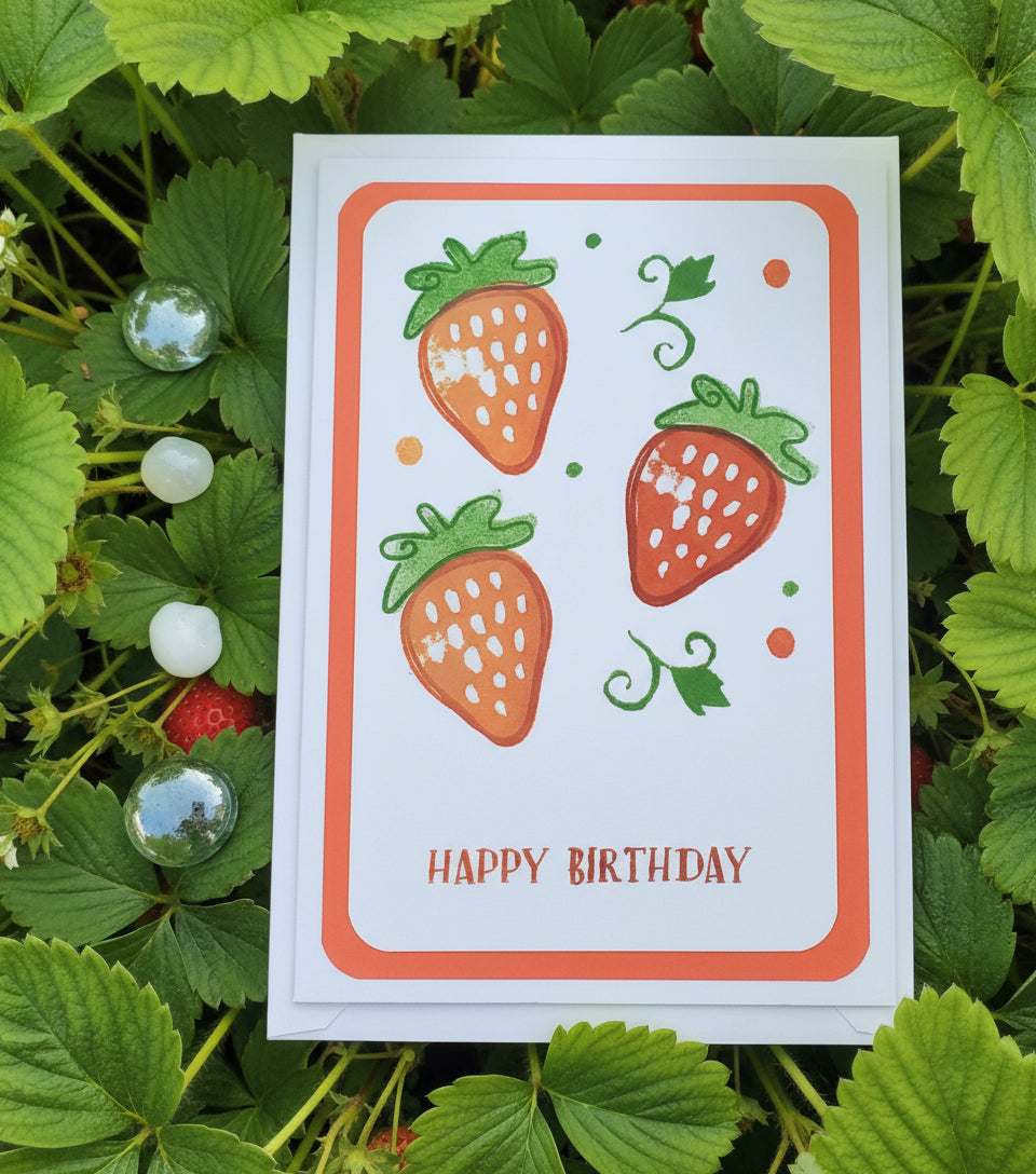 A hand-stamped and layered A6 birthday card with a colorful strawberry design on the front and a white envelope.