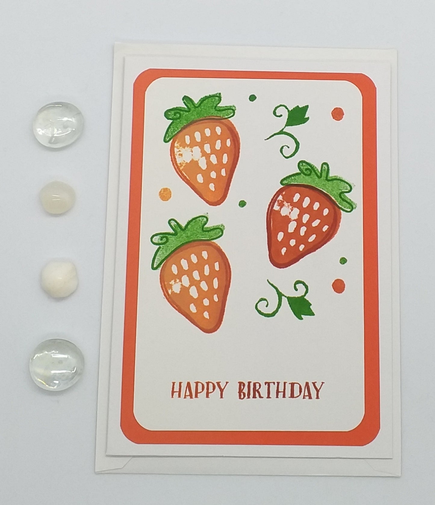 A hand-stamped and layered A6 birthday card with a colorful strawberry design on the front and a white envelope.