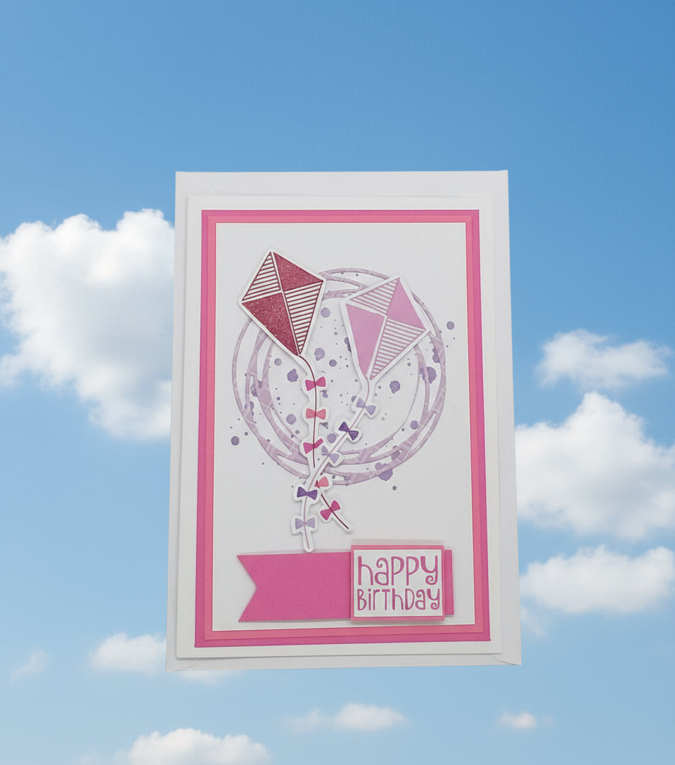 Hand-stamped and layered pink birthday card with a kite design and the words 'Happy Birthday' on the front, accompanied by an envelope.