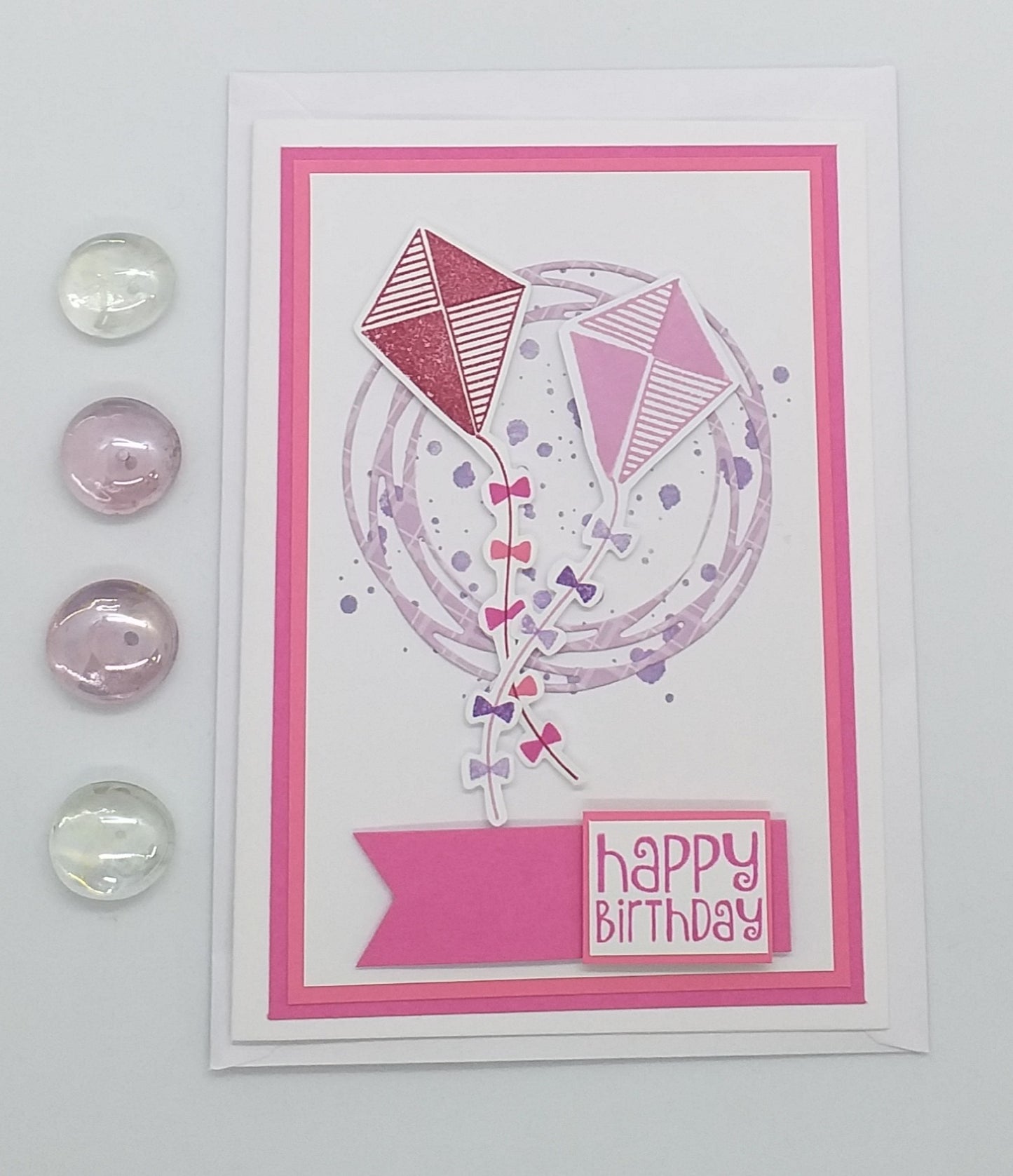 Hand-stamped and layered pink birthday card with a kite design and the words 'Happy Birthday' on the front, accompanied by an envelope.