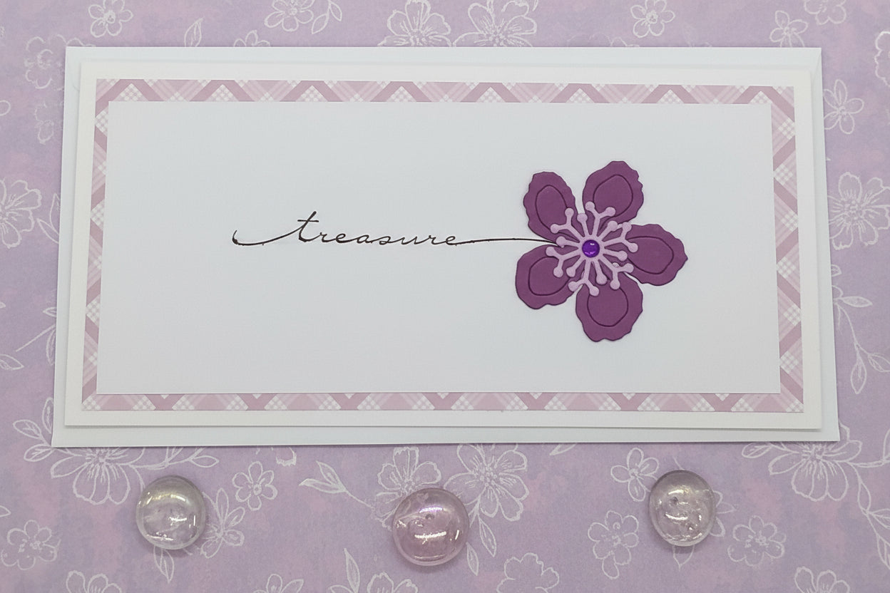 A slimline treasure flower card with a stamped and layered design featuring a die-cut purple flower, accompanied by an envelope.