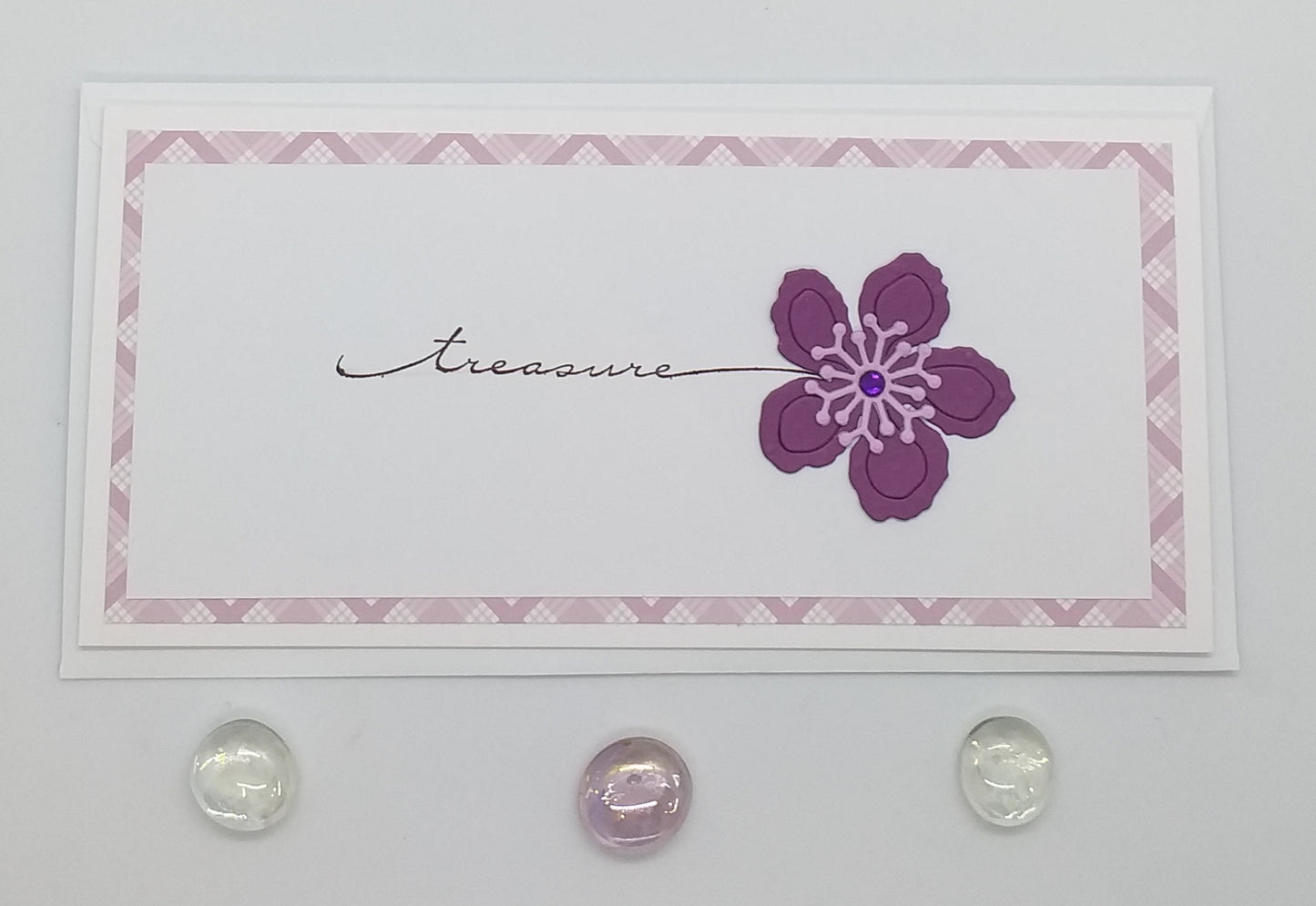 A slimline treasure flower card with a stamped and layered design featuring a die-cut purple flower, accompanied by an envelope.