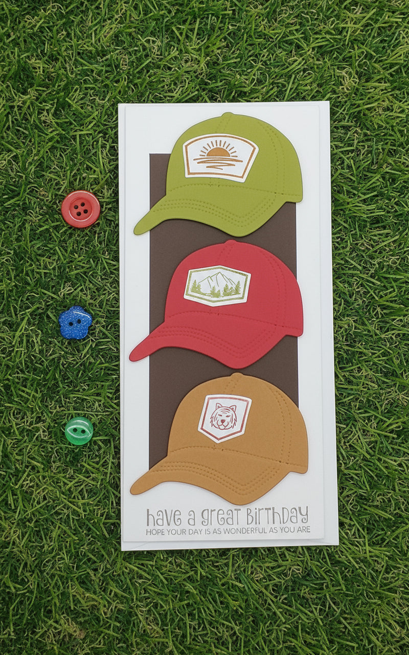 Three colorful baseball caps on a birthday card with decorative buttons on grass