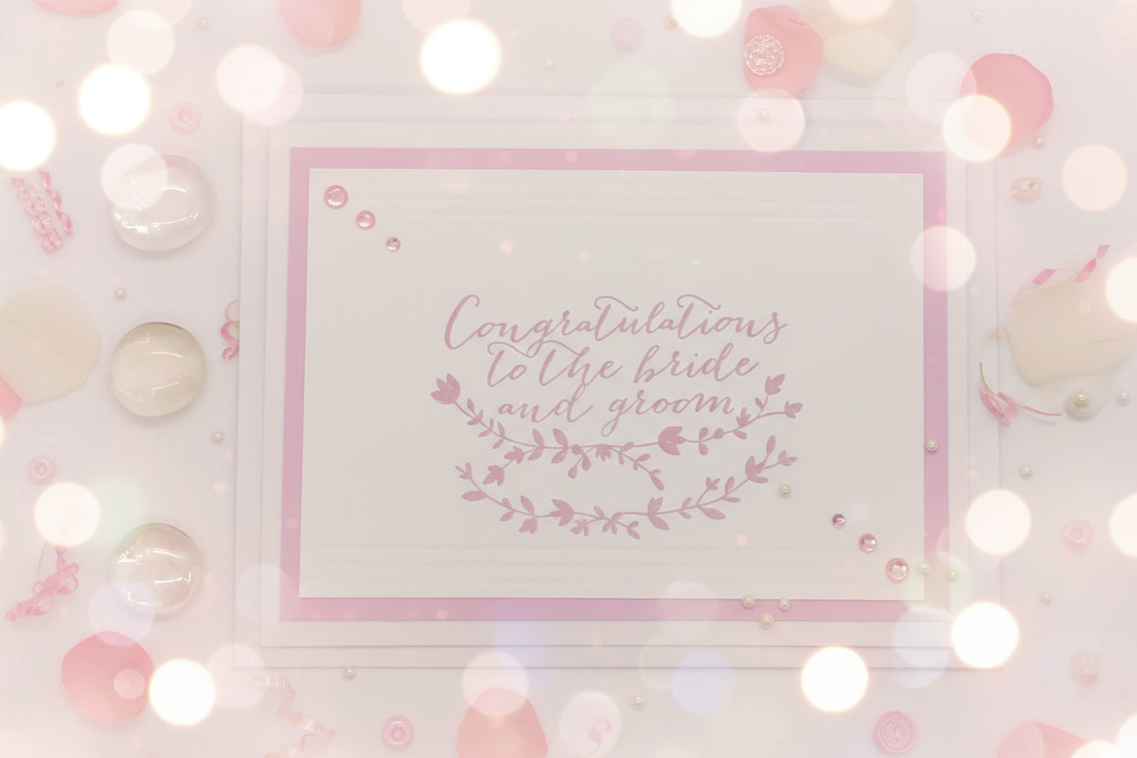 Hand-stamped greeting card with pink and white design, adorned with sparkling gems, and an envelope.