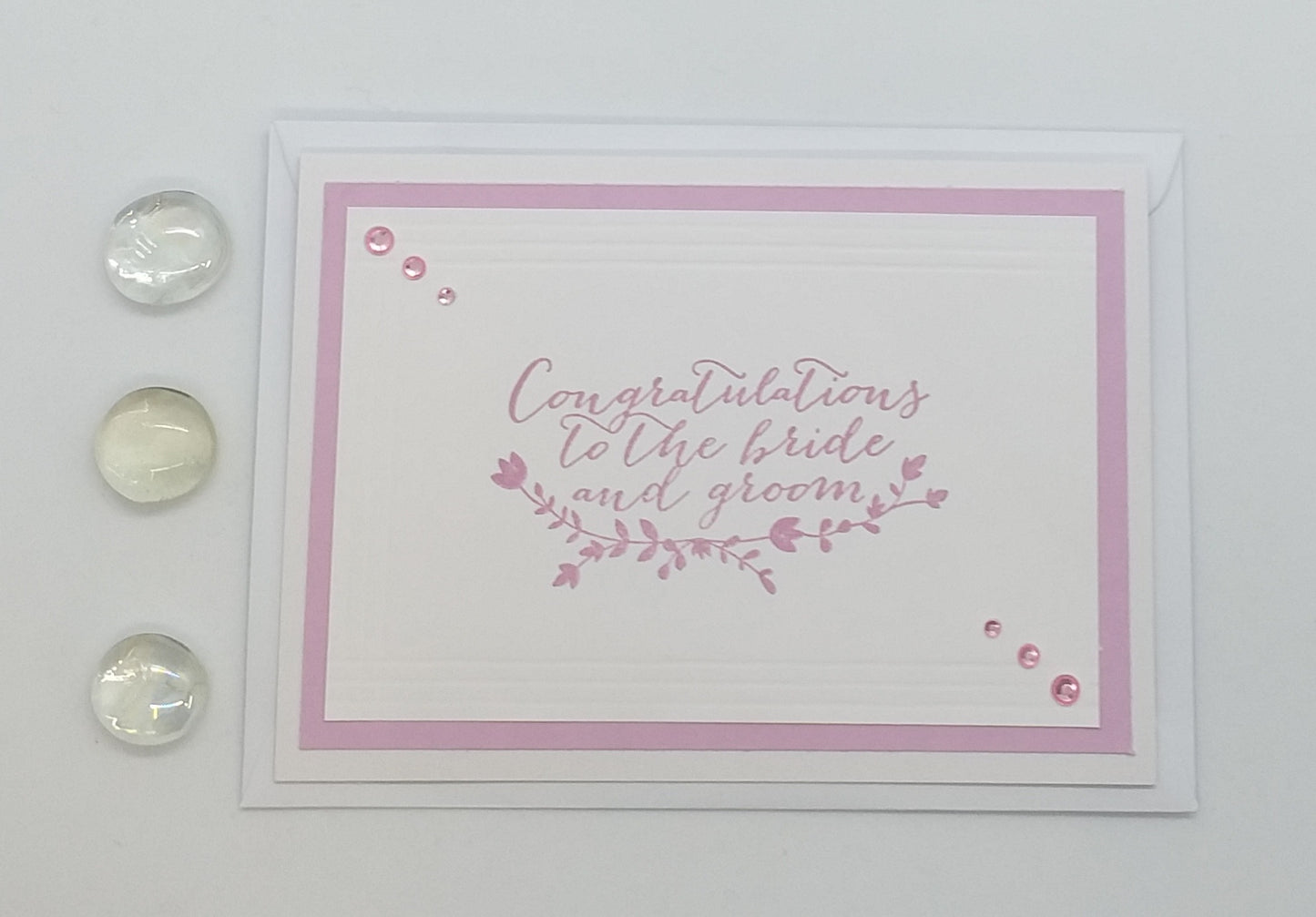 Hand-stamped greeting card with pink and white design, adorned with sparkling gems, and an envelope.