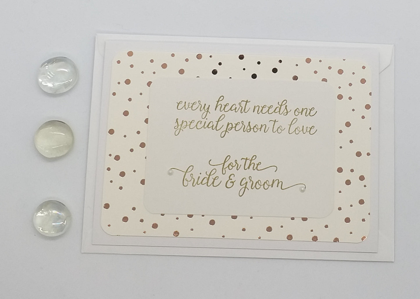 Wedding card with polka dot border and text on a wooden surface with coins.