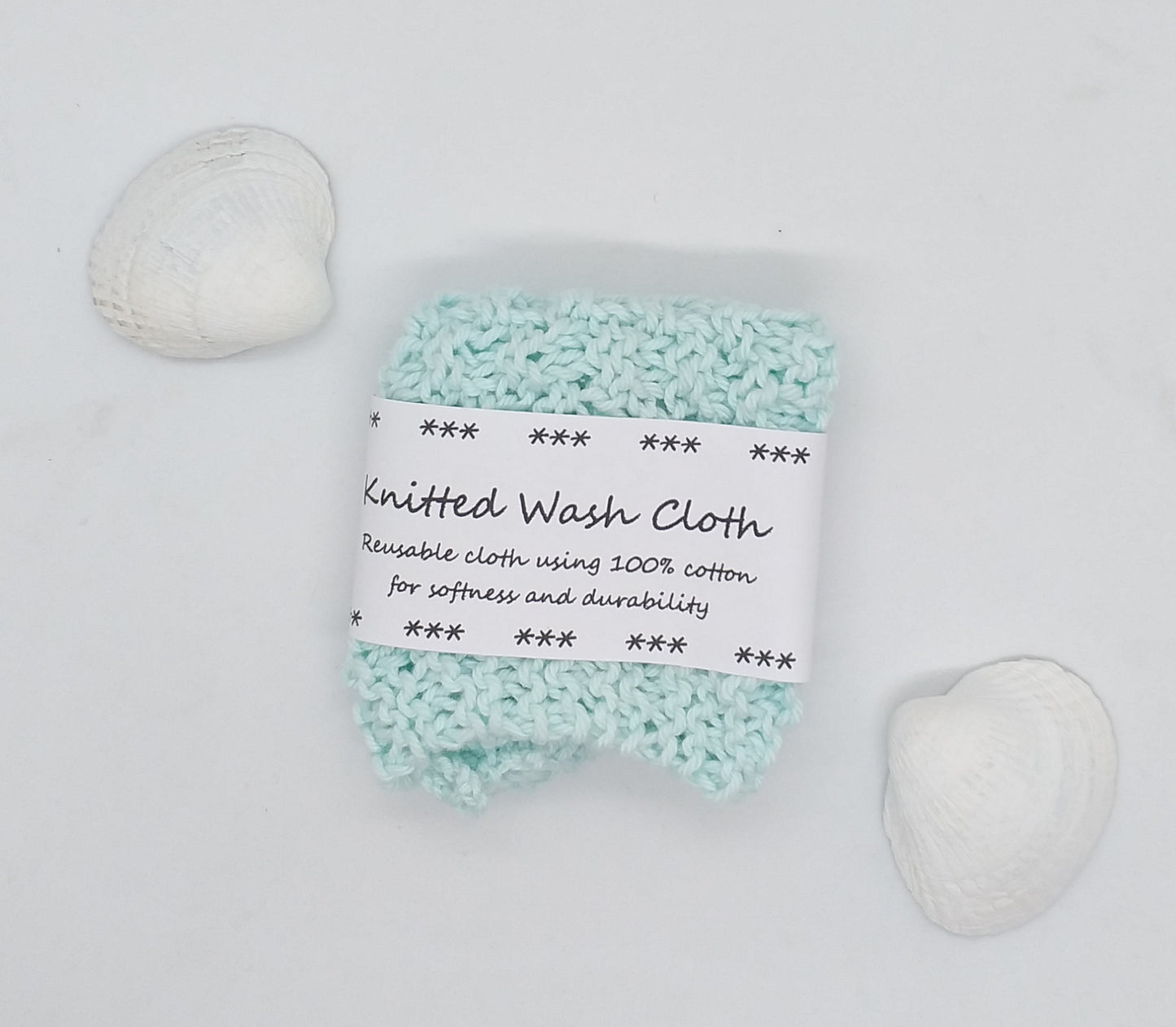 Knitted wash cloth with a label on a wooden surface with seashells.