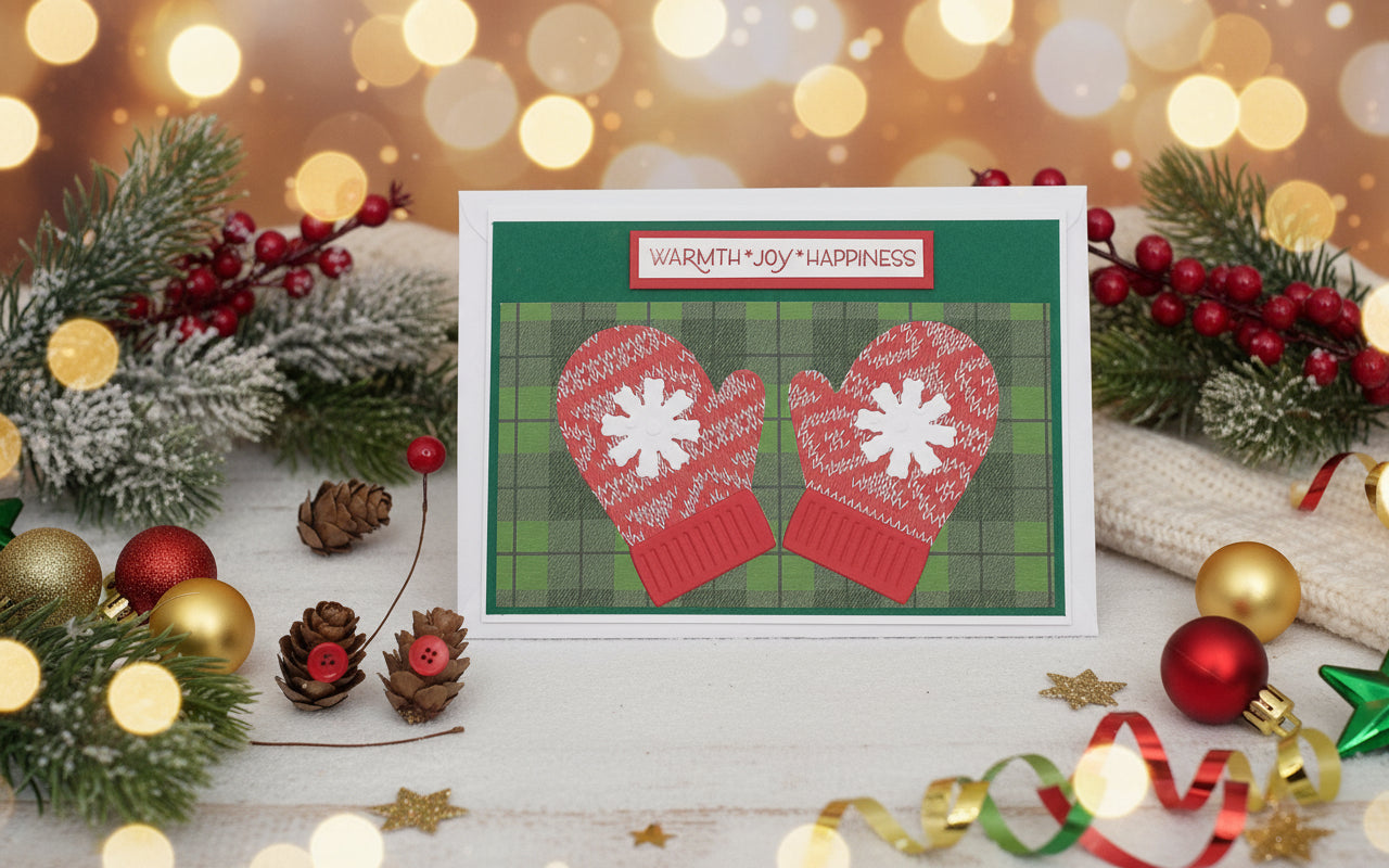 Decorative card with red mittens on a plaid background surrounded by Christmas decorations.