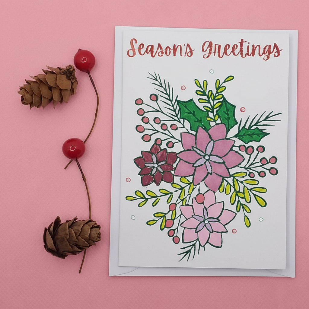 A Season's Greetings Christmas card with a floral design, blank inside for a personal message, displayed with two red berries and a pine cone on a white background.