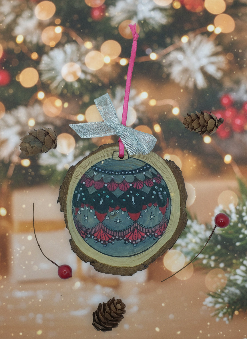 A decorative wood slice bauble with hand-stamped and colored design, adorned with a hanging ribbon, pine cones, and red berries.