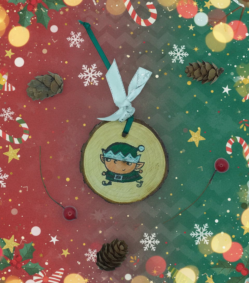 A decorative wood slice with a green elf design, hanging ribbon, and pine cone embellishments on a white background.