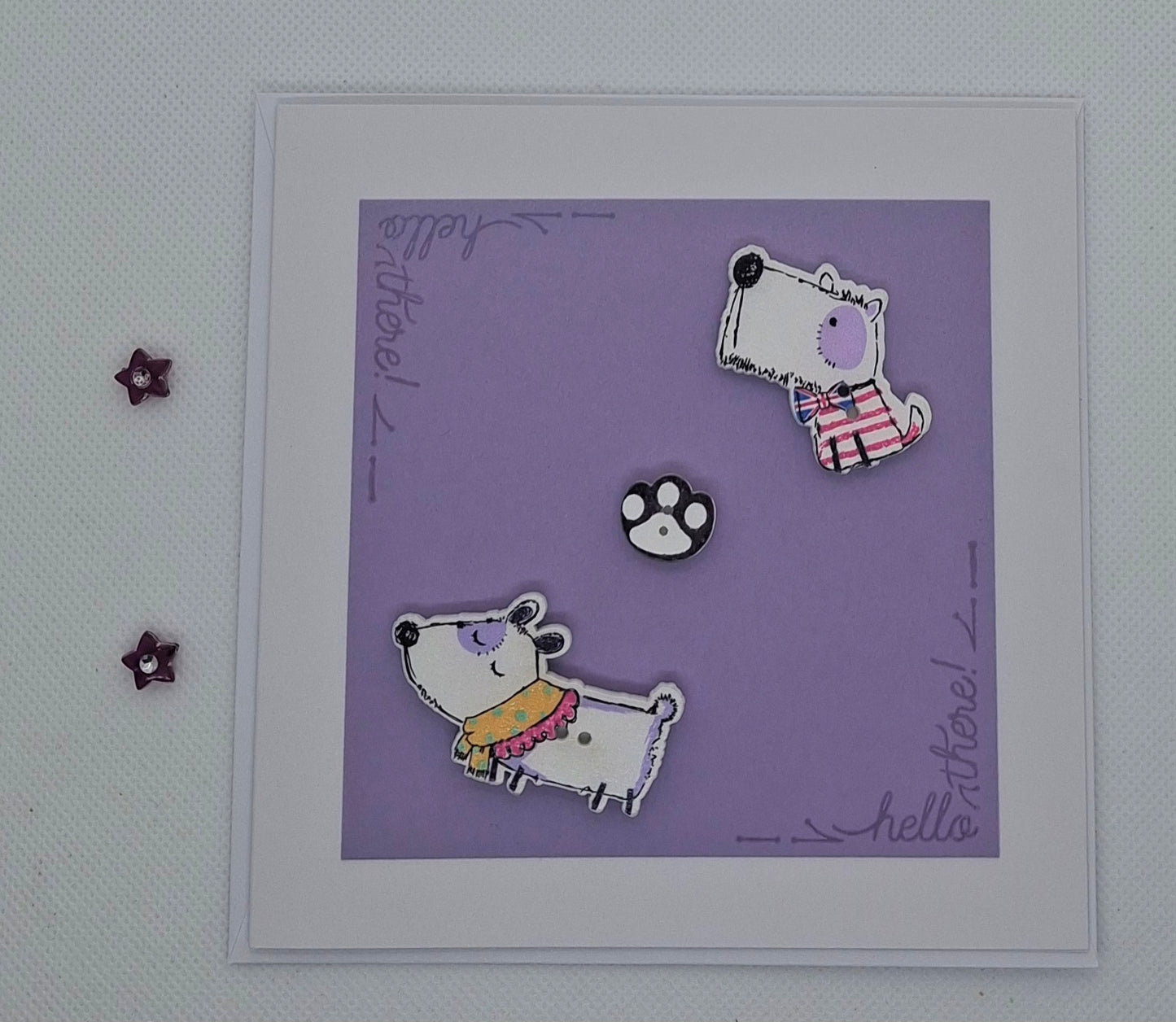 A purple greeting card with two cartoon-style dogs and a paw print, featuring a blank interior and envelope