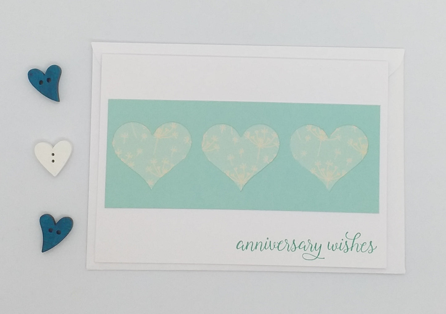 Card with three hearts and 'anniversary wishes' text on a light blue background