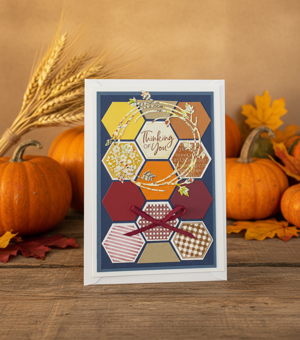 A colorful greeting card with hand-stamped details, a die cut wreath, and a red ribbon, accompanied by a small orange heart-shaped decoration.