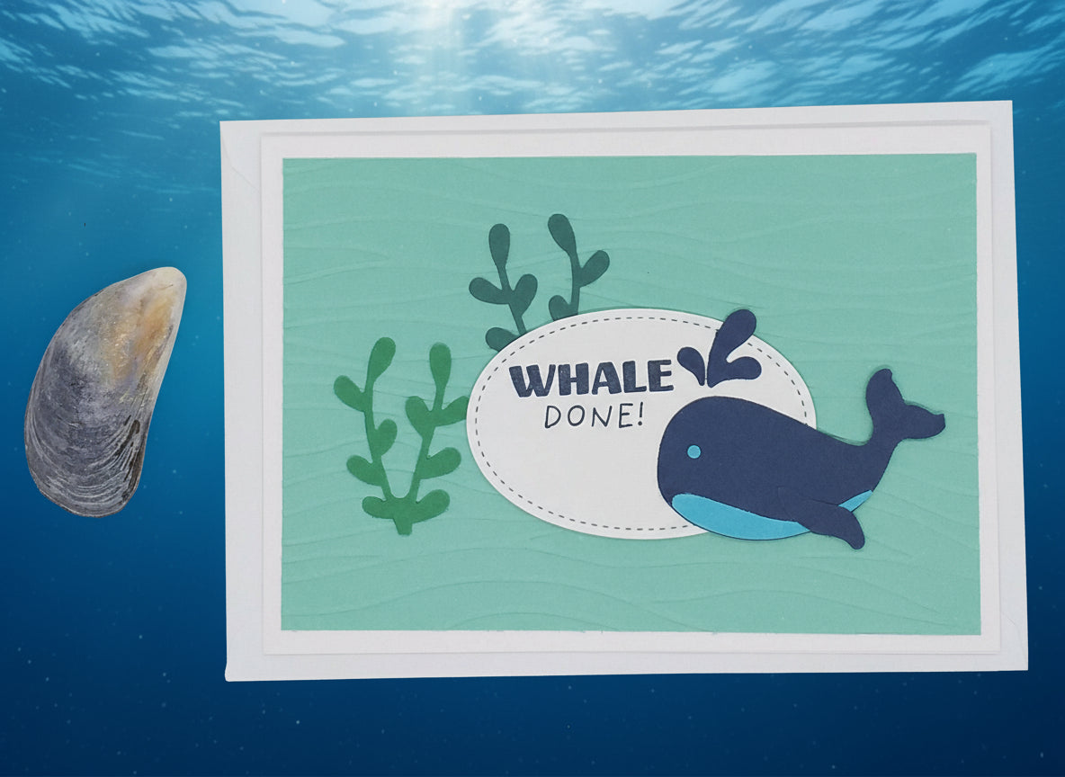 A 'Whale Done' greeting card with a cartoon whale and seaweed design, accompanied by a seashell to the left.