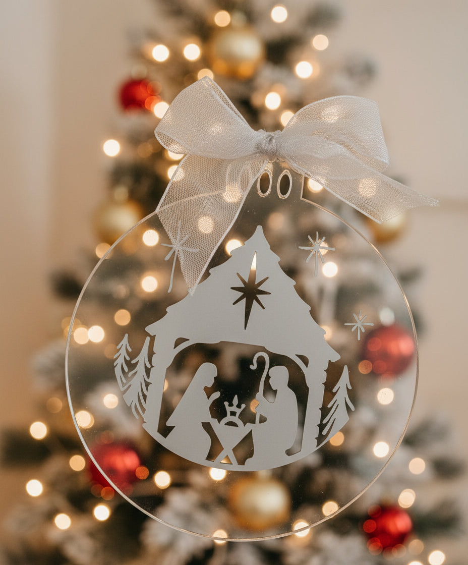 Silver nativity scene Christmas ornament with a white ribbon on a light gray background