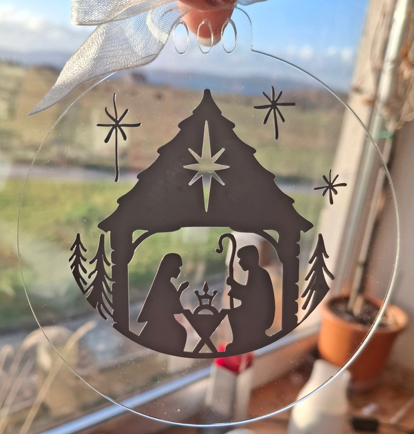 Decorative nativity scene window sticker with stable, star, and figures on a clear background.