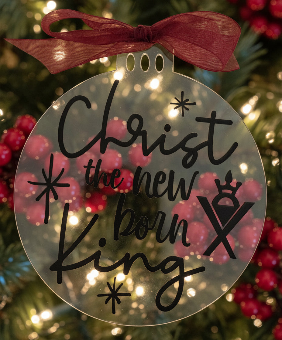 Decorative round sign with 'Christ the new born King' text and a red bow on a white background