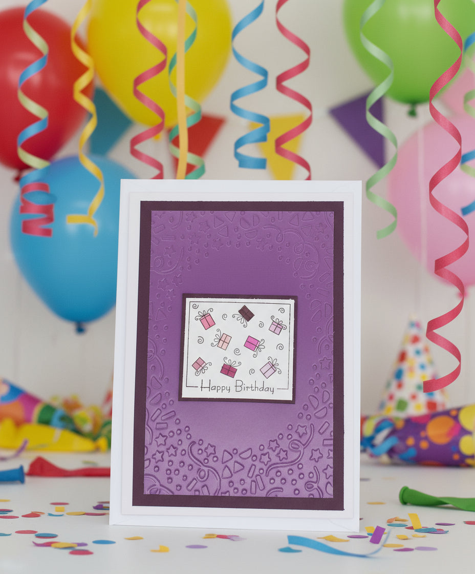 A purple birthday card with a hand-stamped, embossed design and the words 'Happy Birthday' displayed. The card is accompanied by two clear embellishments on the side.