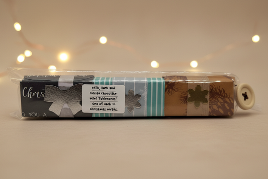 Three-flavour Toblerone Christmas gift pack in handmade triangular boxes inside a cello sleeve with a decorative button