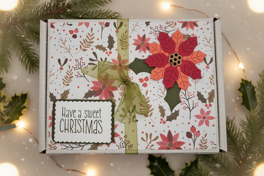 Poinsettia Christmas Divine chocolate gift box with a festive evergreen and warm fairy-light background