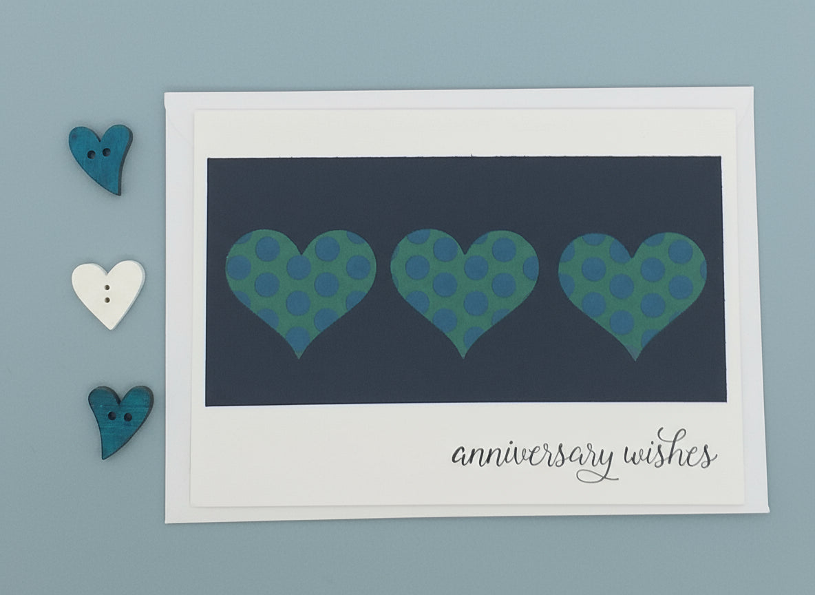 Card with three polka dot hearts and 'anniversary wishes' text on a blue background